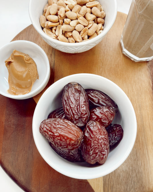 Fresh organic Medjool dates in a bowl surrounded by date shake ingredients, featuring milk, vanilla ice cream, and spices, presented by Arizona Date Company.